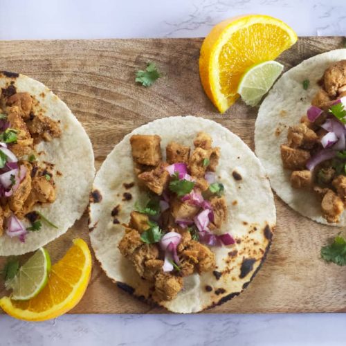 3 chicken tacos garnished with onion and cilantro