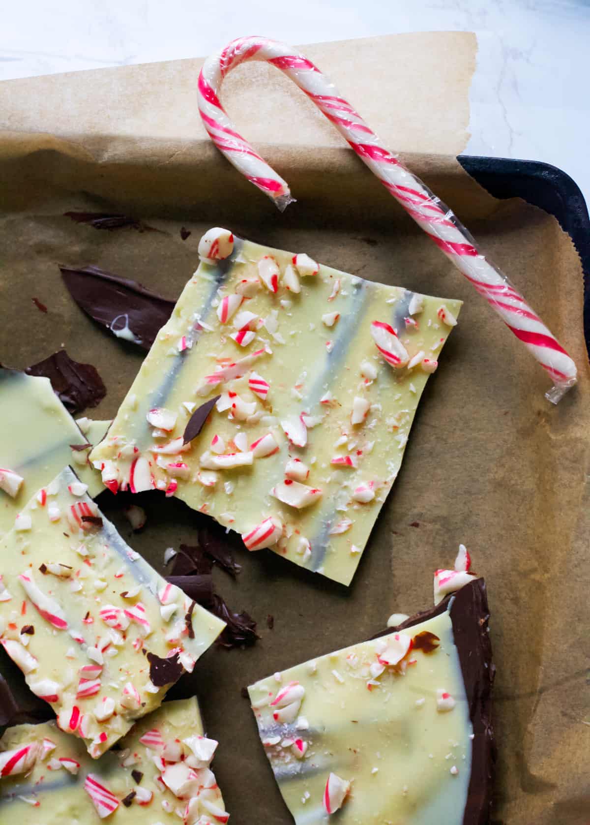 low sugar peppermint bark broken apart with a candy cane
