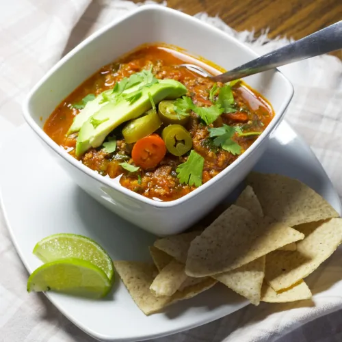 paleo taco soup with tortilla chips and a lime wedge