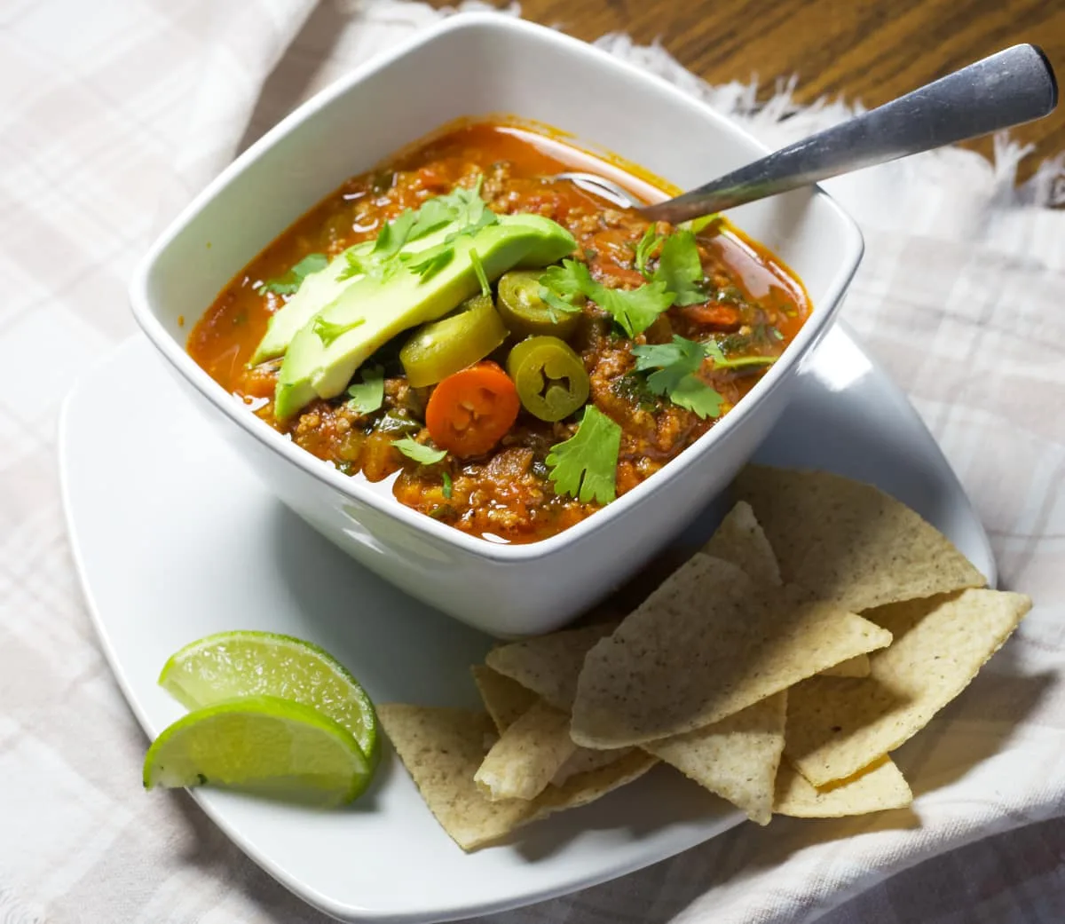 paleo taco soup with tortilla chips and a lime wedge