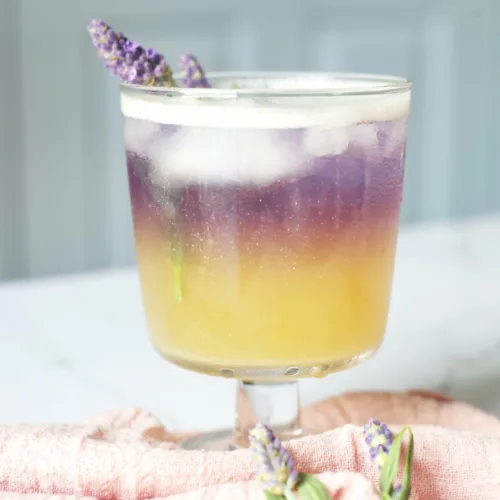 an ombre yellow and ombre cocktail with a lavender sprig garnish