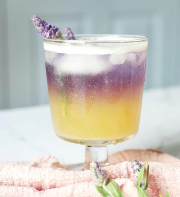 an ombre yellow and ombre cocktail with a lavender sprig garnish