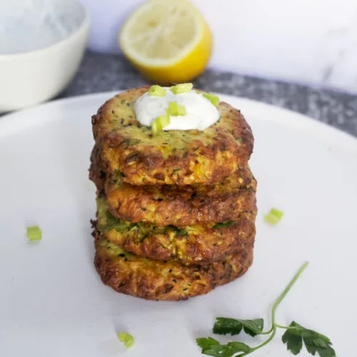 crispy zuchinni fritters stacked with a dollop of yogurt sauce on top