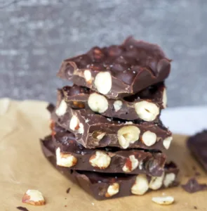 dark chocolate bars stacked on top of one another with hazelnuts inside.