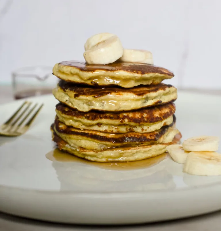 loight fluffy pancakes stacked with sliced banana on top